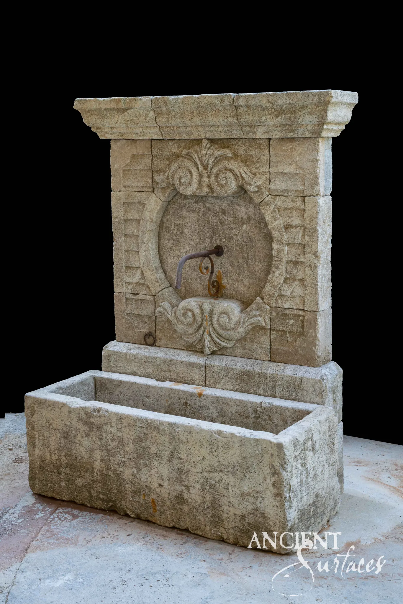 Limestone wall fountain with a carved oval acanthus cartouche above a rectangular trough